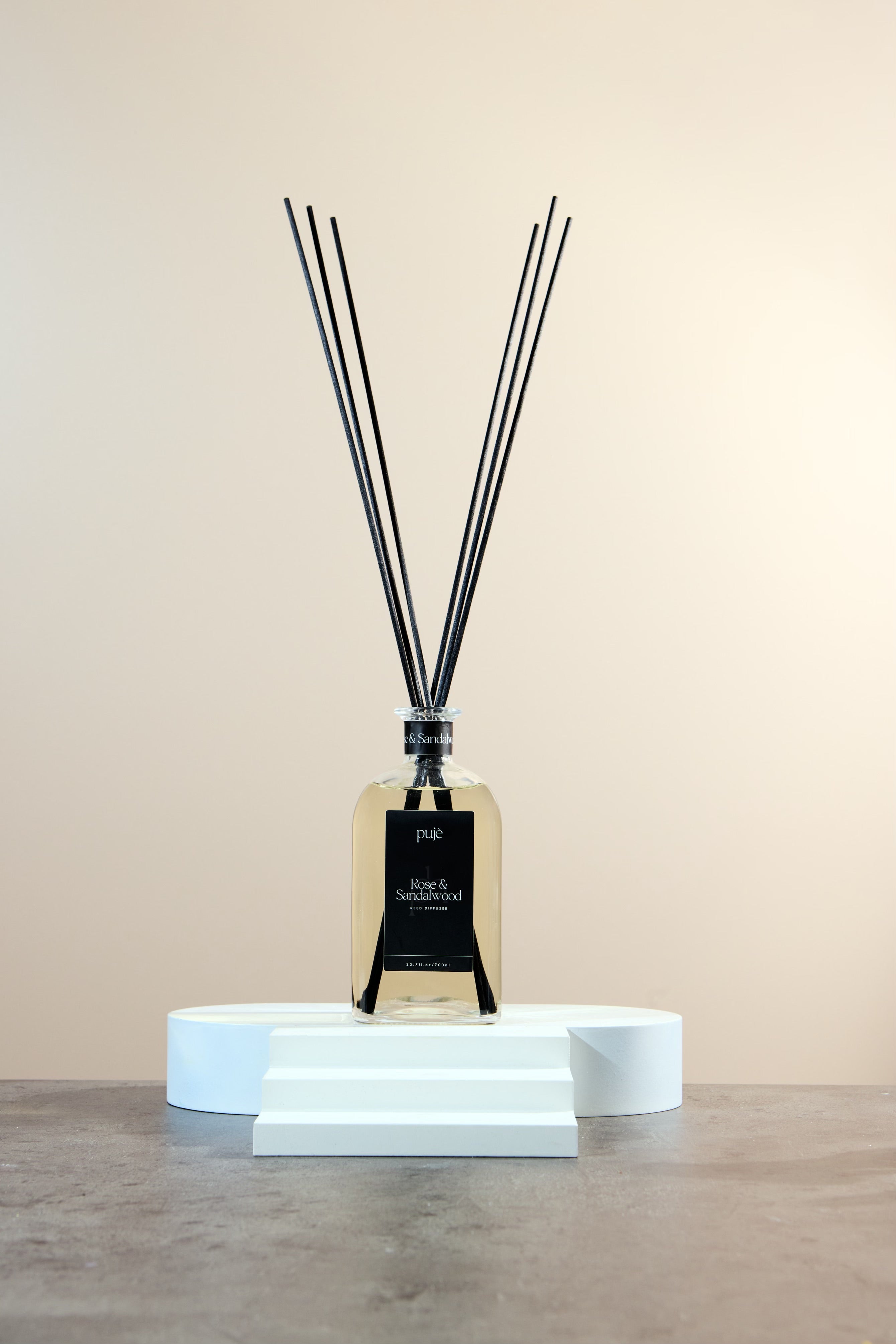 A glass bottle diffuser with black reeds and a black label that reads