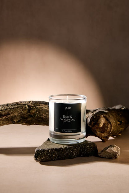 A glass soy wax candle with a black label that reads "Rose & Sandalwood" Scented.