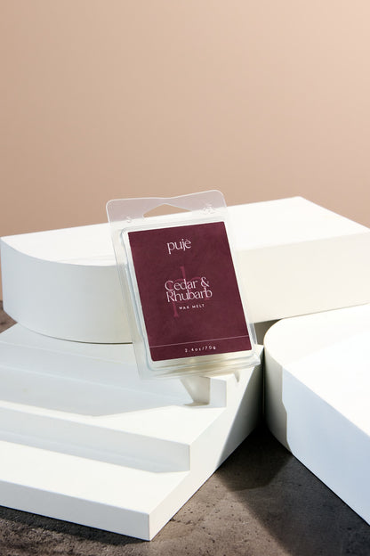 A soy wax melt with a burgundy label that reads "Cedar & Rhubarb" Scented.