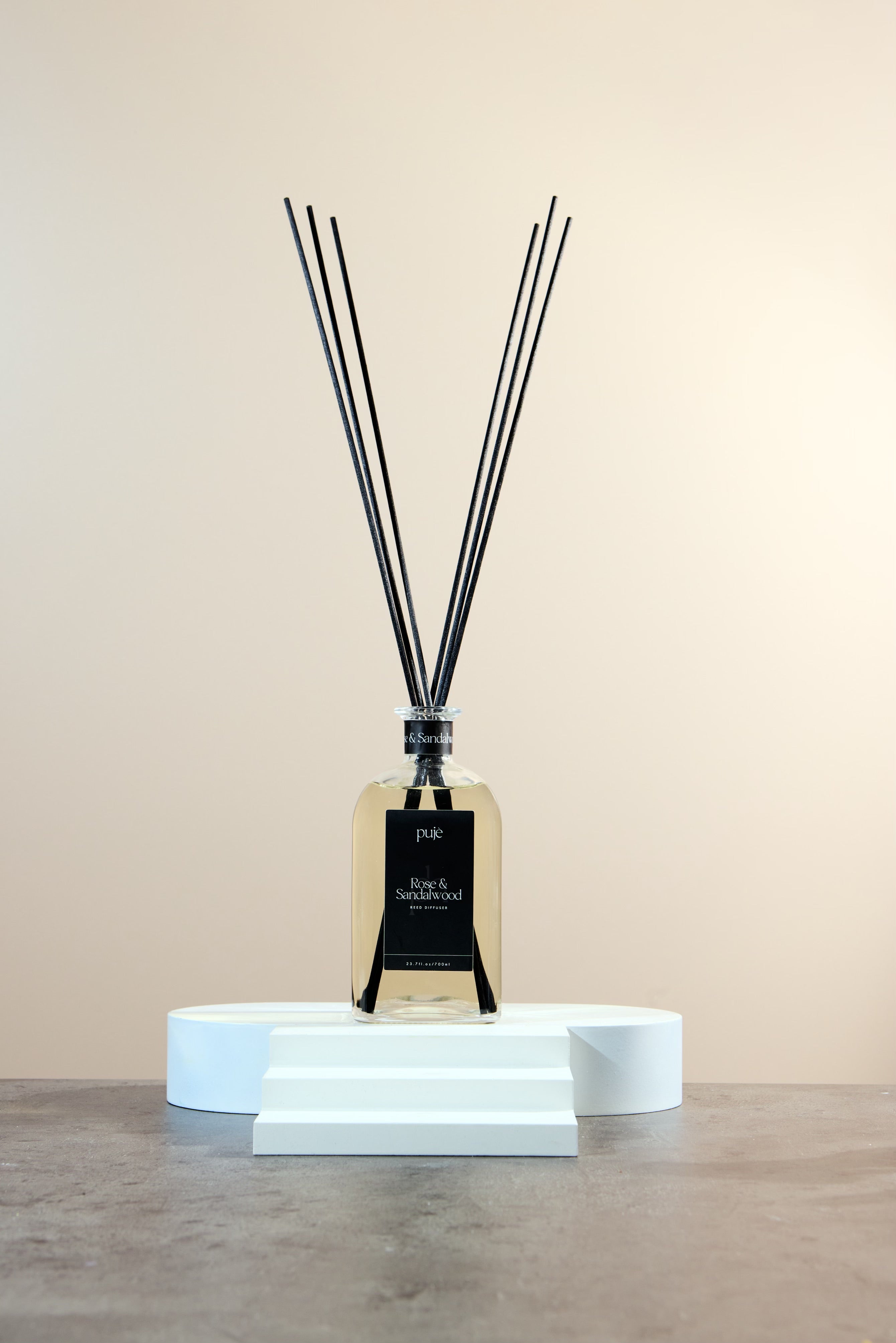 A glass bottle diffuser with black reeds and a black label that reads 