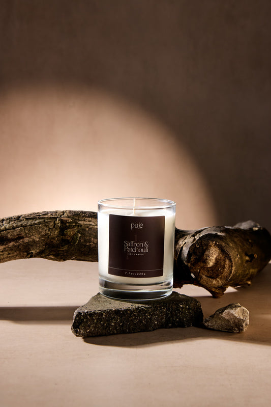 A glass soy wax candle with a brown label that reads "Saffron & Patchouli" Scented.