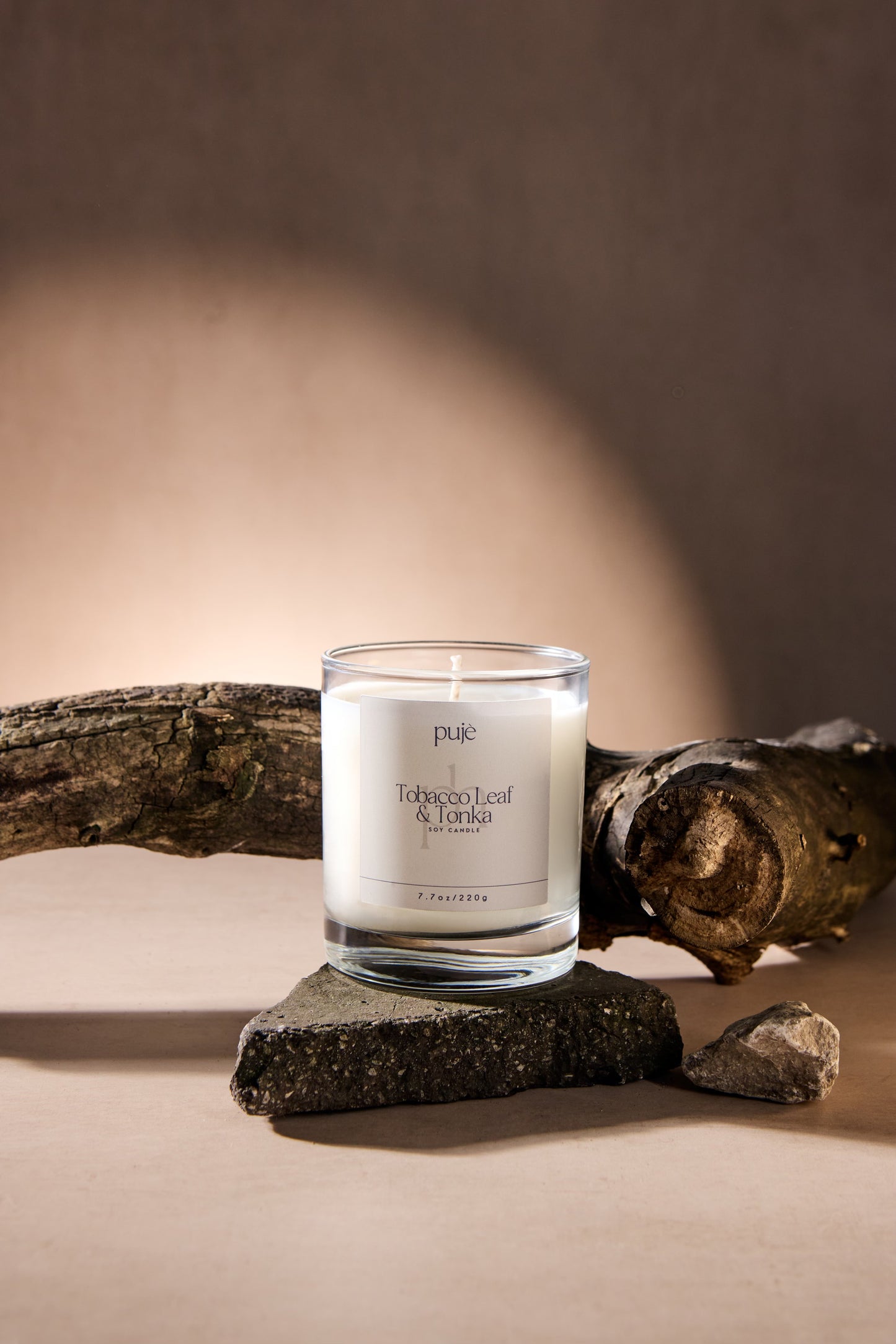 A glass soy wax candle with a silver nude label that reads "Tobacco Leaf & Tonka" Scented.